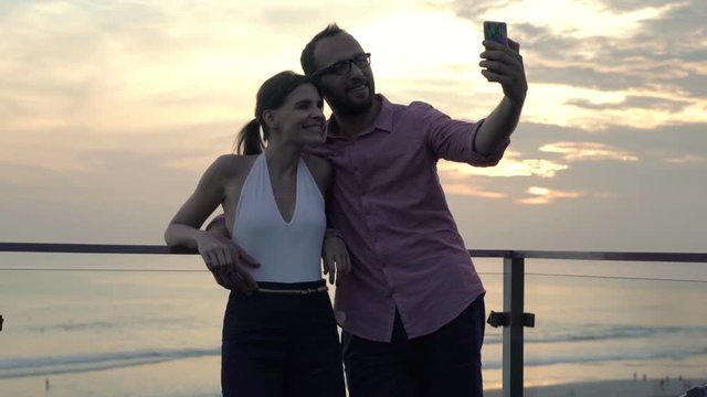 Young couple taking selfie photo with cellphone on terrace 

