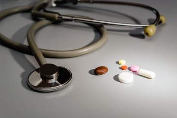 Stethoscope close-up, next tablets and capsules.