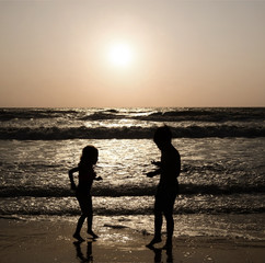 Silhouettes of children on a sea beach