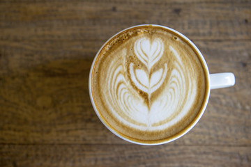 Closeup hot coffee latte over vintage wooden table background