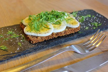 Traditional danish open sandwich with egg, sour cream, dill, salt and pepper