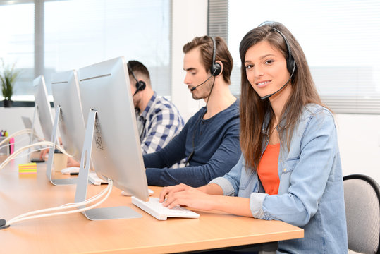 group of young people telephone operator with headset working on desktop computer in row in customer service call support helpline business center