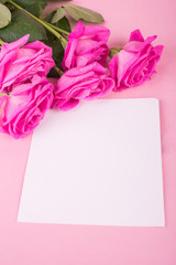Pink roses and plaque on a wooden background