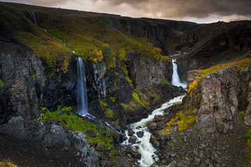 Cloudy sunset over the cliff with stunning waterfall at Hengifoss, Iceland