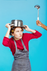 Fototapeta na wymiar Nice woman with saucepan on head hides from ladle