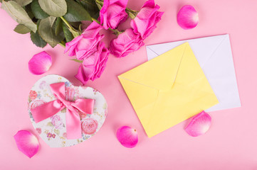 Pink rose and envelope on a wooden background