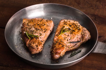 Fried meat and rosemary in a frying pan