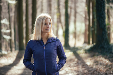Fit woman standing in forest, close up.