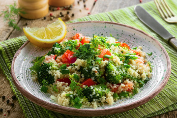 Delicious healthy meal made of couscous, broccoli and other vegetables on a rustic wooden table....