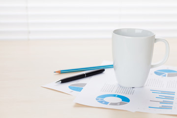 Office workplace with coffee, supplies and reports