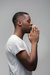 Praying african american man hoping for better. Asking God for good luck, success, forgiveness. Power of religion, belief, worship. Holding hands in prayer, eyes closed. © golubovy