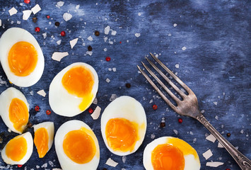 Fototapeta na wymiar Hard boiled eggs, sliced in halves on wooden table