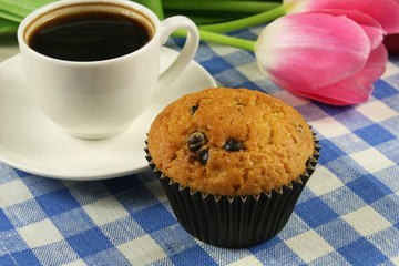Chocolate muffins with a Cup of coffee and flowers on the table