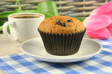 Chocolate muffins with a Cup of coffee and flowers on the table