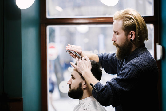 Profile of barber cutting man's hair