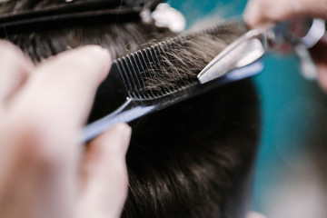 Obraz premium Barber cuts man's hair with scissors