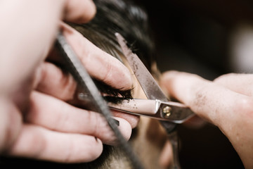Barber holds man's hair in fingers while he cuts it
