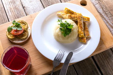 potato puree with minced steak on a wooden table, fruit compote in a glass
