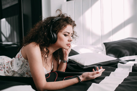 Woman listens to the music attentively lying on bed