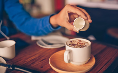 Fototapeta na wymiar Man hand pouring a syrup onto a hot coffee cup.