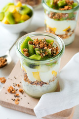 Yogurt granola parfait with mango,kiwi, tropical fruits аnd сhia seeds, layered dessert or breakfast. Selective focus.