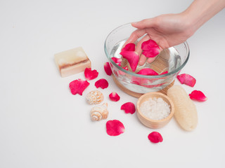 Aromatherapy  product  Spa massage set, candle and red rose in tray .Woman  hand washing water on  white wood background .