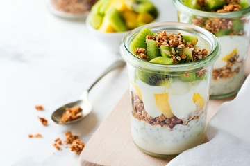 Yogurt granola parfait with mango,kiwi, tropical fruits аnd сhia seeds, layered dessert or breakfast. Selective focus.
