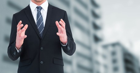 Business man mid section with hands up against blurry building
