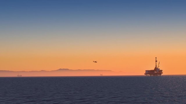  Helicopter landing on the offshore oil rig at sunset off Huntington Beach on the California coast