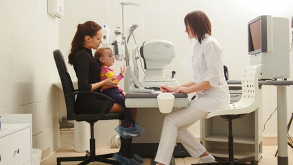 Child with Mother in eye clinic - children ophthalmology - optometrist Checks Child's Eye