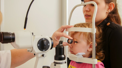 Child's ophthalmology - doctor optometrist checks eyesight for patient - little girl - obrazy, fototapety, plakaty