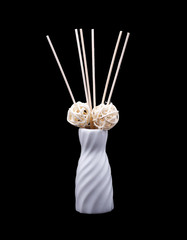 White ceramic vase with wooden ornaments isolated on a black background.