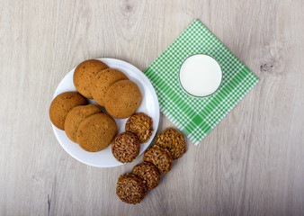 Glass of milk and cookies on a wooden table, top view
