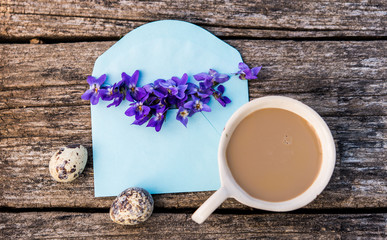 Violet flowers in blue envelopeand coffe and egg decoration