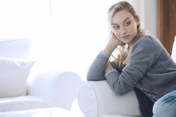 Young beautiful woman sitting on couch at her room