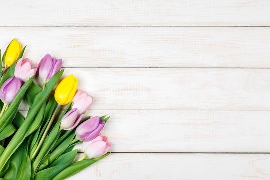 Bunch of colored tulips on a white wooden background