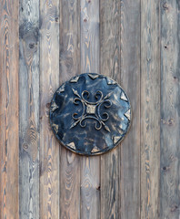 Medieval iron shield on a wooden wall