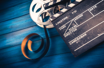 movie reel, film and clapper on a wooden background
