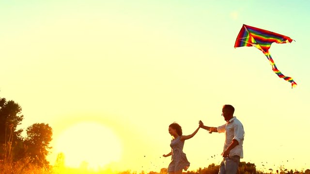 Beauty young couple running with flying colorful kite over clear sky. Slow motion 240 fps. 4K UHD video