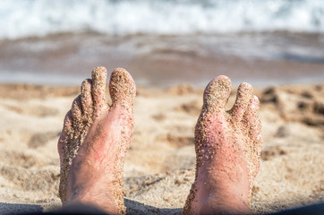 Men's legs in the sand on the beach