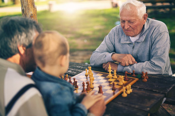 Active retired people, old friends and free time, two senior men having fun and playing chess at...