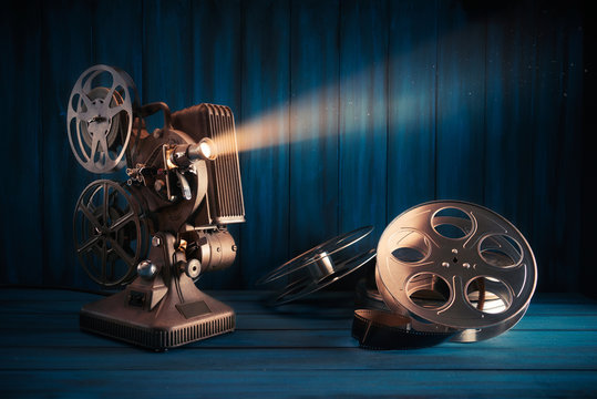 vintage 8mm movie projector with 35mm reels and film on a wooden background  with dramatic lighting Stock Photo