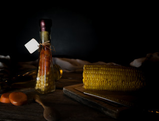 bottle of canned carrots and corn, spices on a wooden table. Dark background