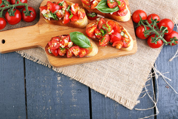Tasty savory tomato Italian appetizers, or bruschetta, on slices of toasted baguette garnished with basil