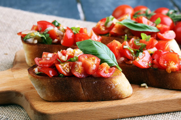 Tasty savory tomato Italian appetizers, or bruschetta, on slices of toasted baguette garnished with basil