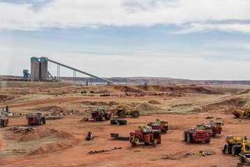 Industrial coal mining equipment and silos beside a row of railway cars in a Wyoming valley landscape