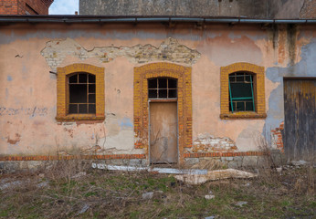 Old, destroyed building with door and two windows.