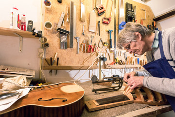 Luthier concentrating on carving a lute