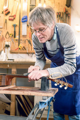 Guitar repairer filing the frets of an acoustic guitar