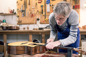 Luthier filing the frets of an acoustic guitar